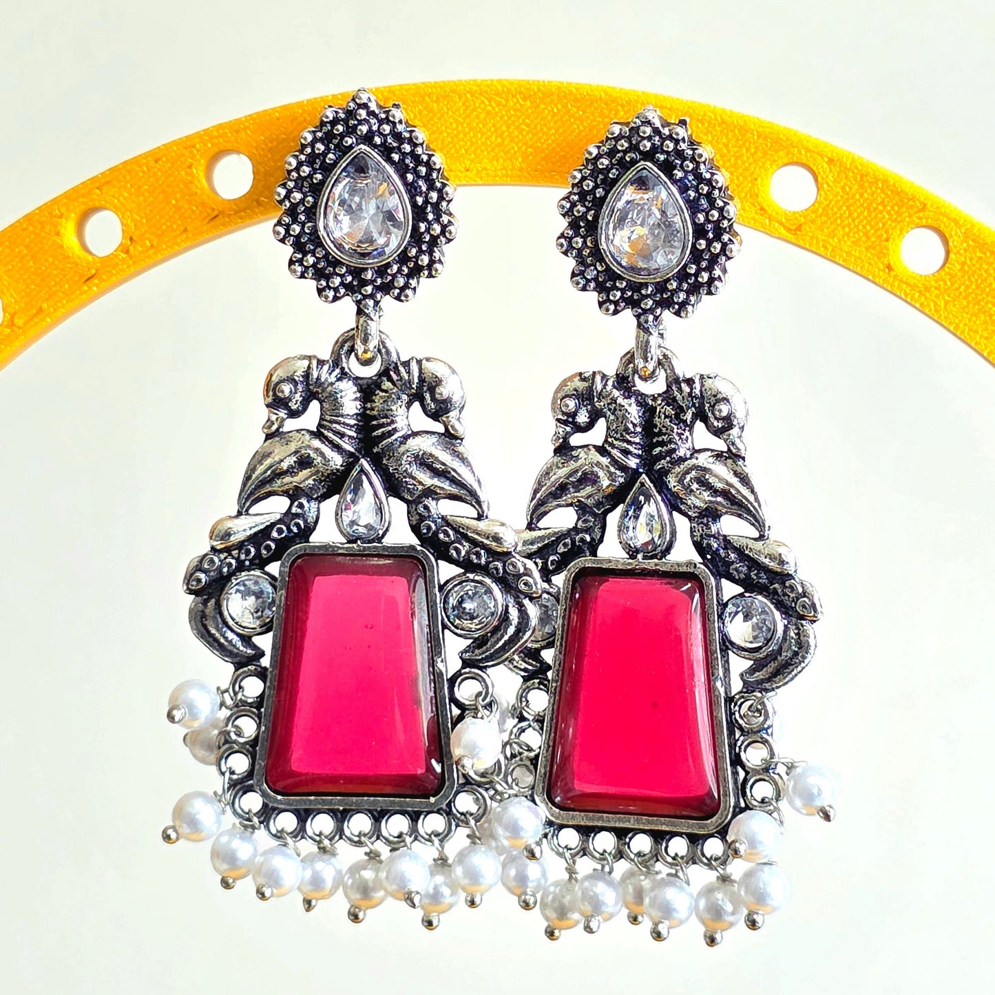 Decorative earrings with pink stones on a yellow and white background