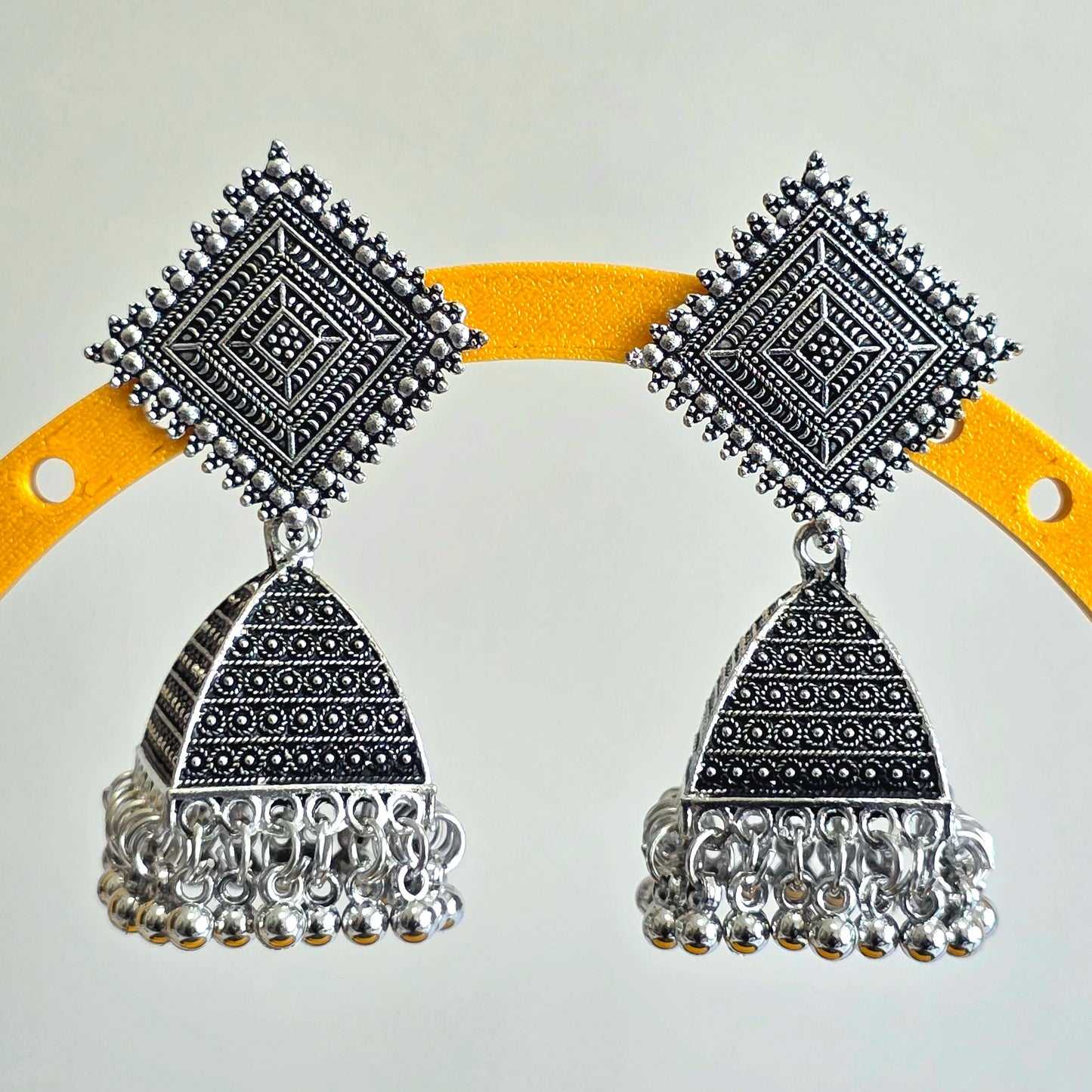 Pair of silver earrings on a yellow and gray background