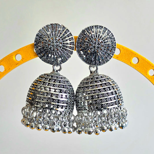 Silver jhumka earrings on a yellow arch with a white background