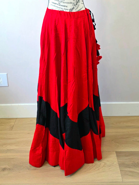 Mannequin wearing a red and black dress with a white top on a wooden floor.